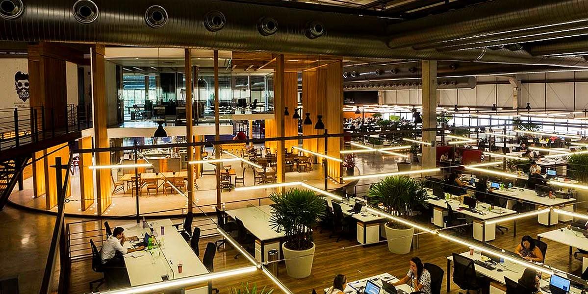Escritório amplo com mezanino, iluminação linear e estações de trabalho